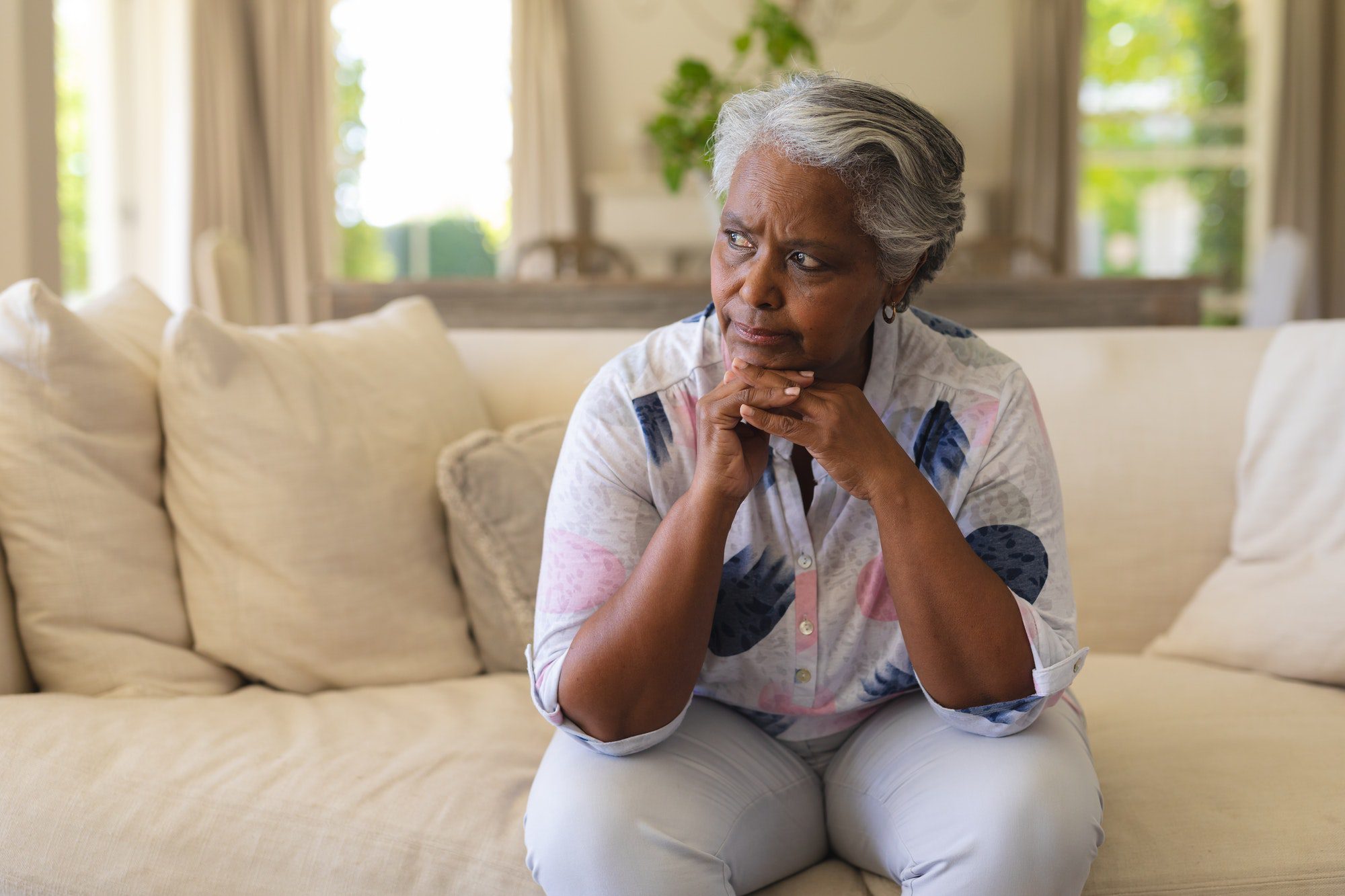 Senior african american woman sitting on sofa and thinking of her High Deductible Plan G