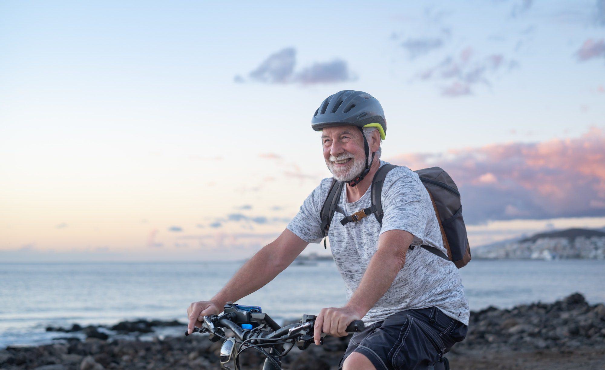 Happy senior cyclist man at the beach at sunset enjoying freedom and beauty in nature Medicare Advantage C