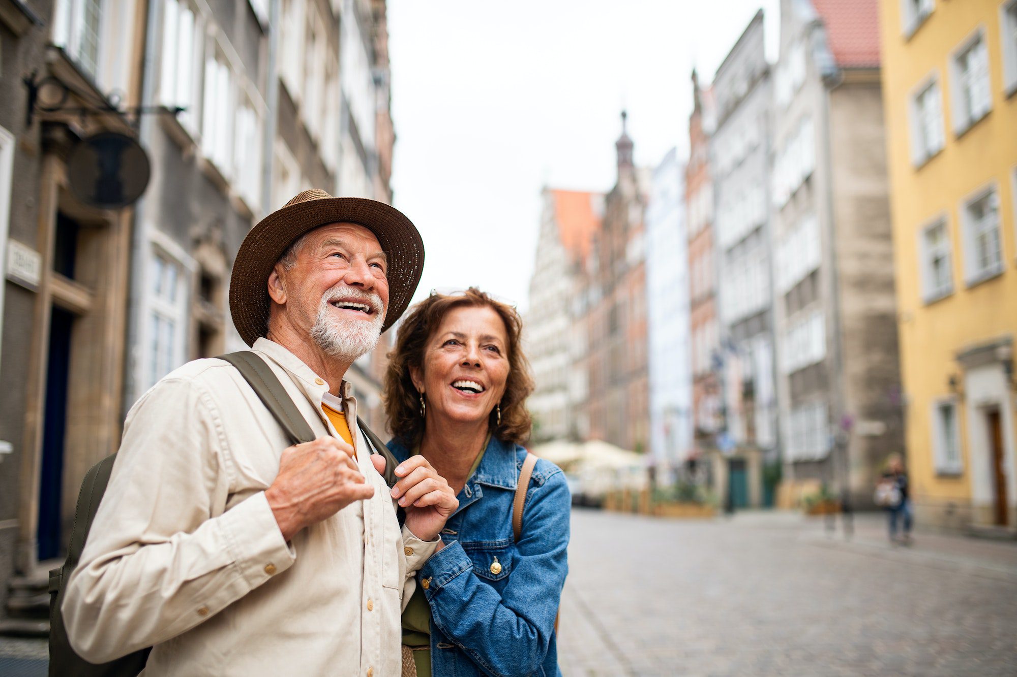 Portrait of happy senior couple tourists outdoors in historic town with Medigap Plan C