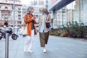 Cheerful senior woman with long haired companion walk on large city street with Medicare Advantage CSNP