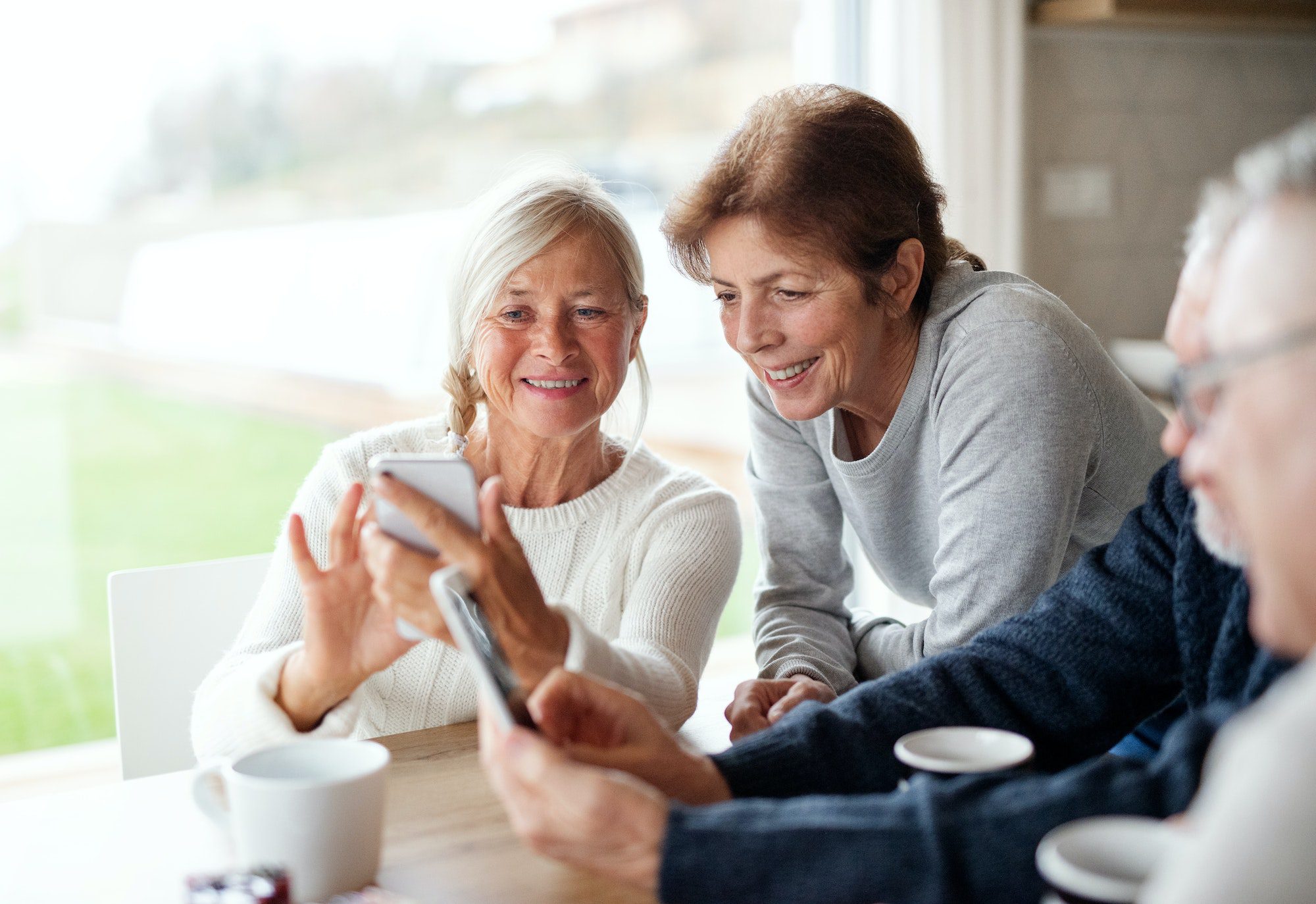 Group of senior friends at home, using smartphones with Medicare Advantage Plan