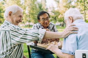 Group of senior friends playing chess at the park with new 2023 Medicare Premiums and Deductibles