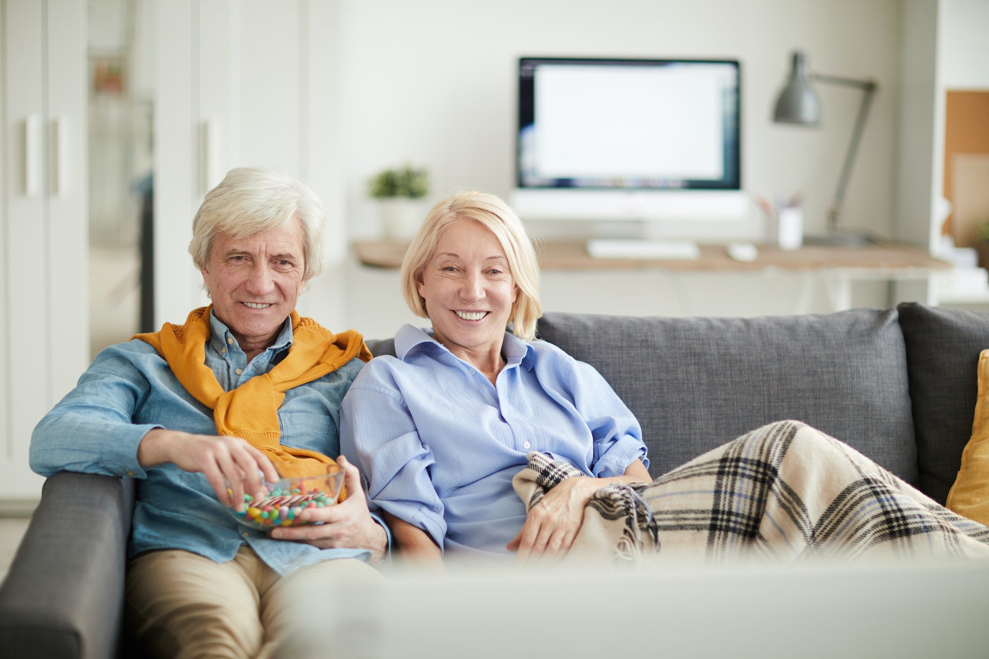 Modern Senior Couple Watching TV learning about Medicare Mistakes