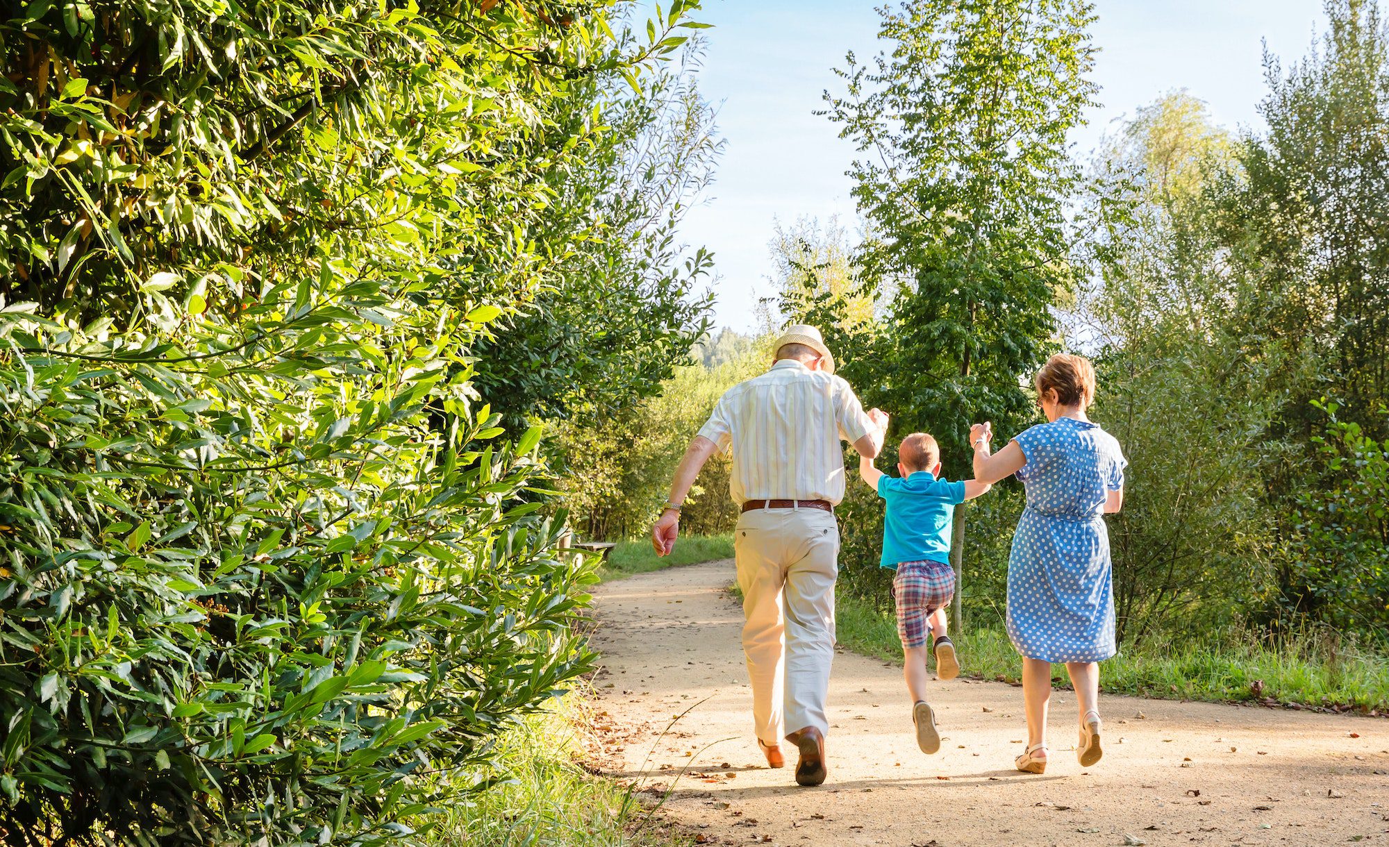 Grandparents and grandchild jumping outdoors with new 2023 Medicare Premiums