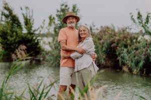 Happy senior couple hugging on walk near the lake during autumn day with Medicare Advantage Plan