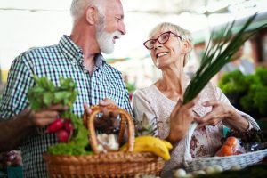 Senior shopping couple with basket on the market. Healthy diet with Medicare Grocery Allowance