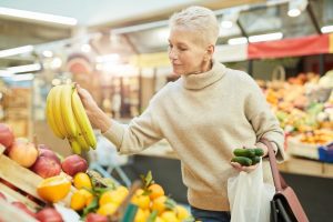 Senior Woman Grocery Shopping at Farmers Market. Saving money on out-of-pocket Medicare Costs