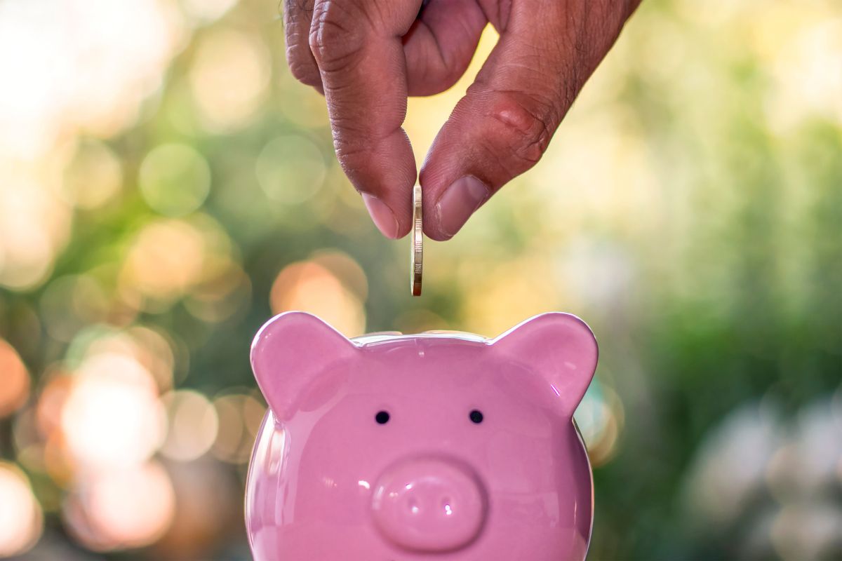 Beneficiary putting coins in piggy bank - saving money on Medicare