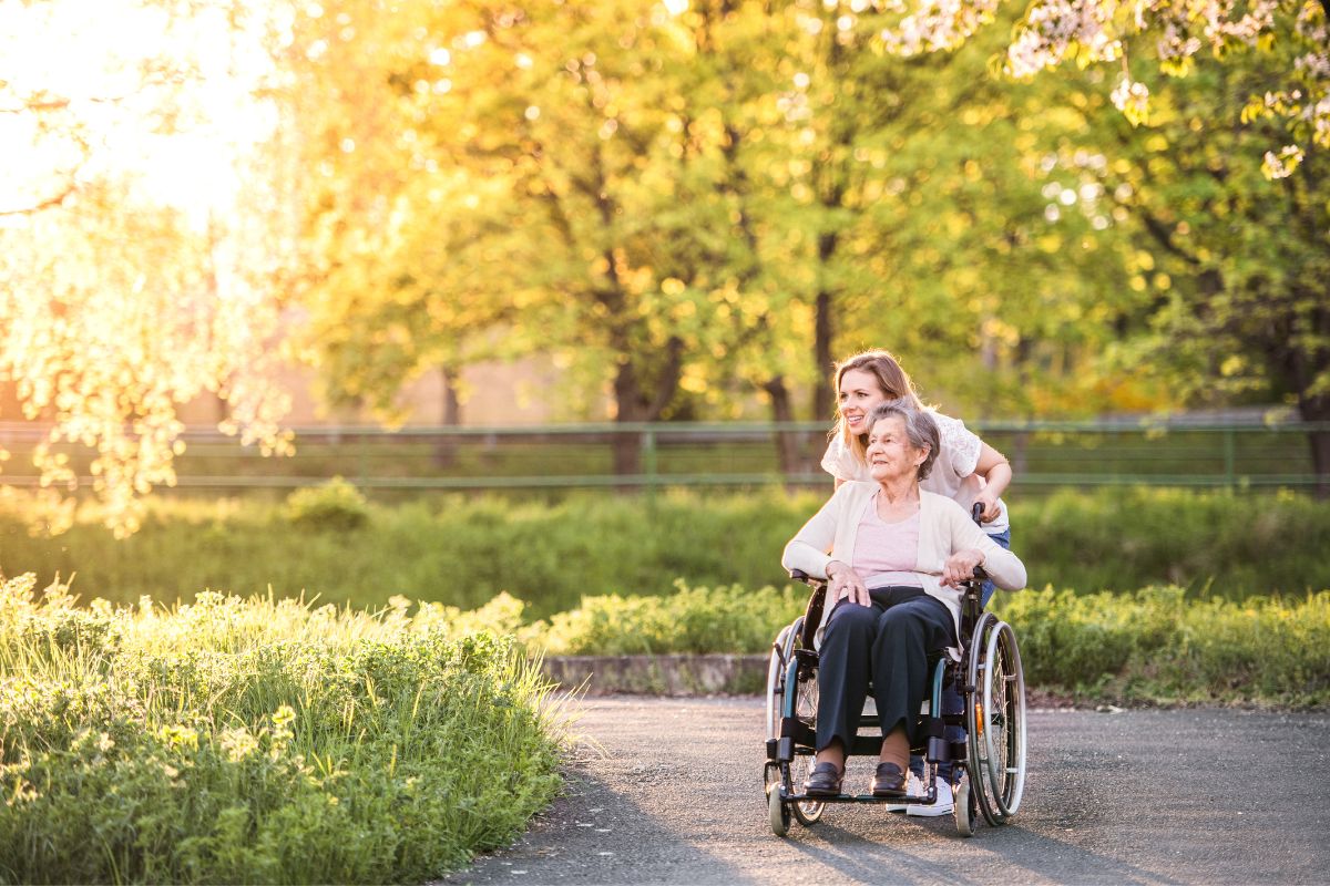 Woman pushing older woman in wheelchair