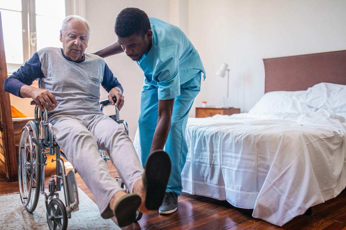 Nurse helping man into wheelchair in a skilled nursing facility
