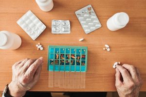 Person filling their weekly prescription planner
