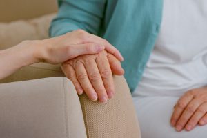 Woman holding older woman's hand, getting ready for long-term care